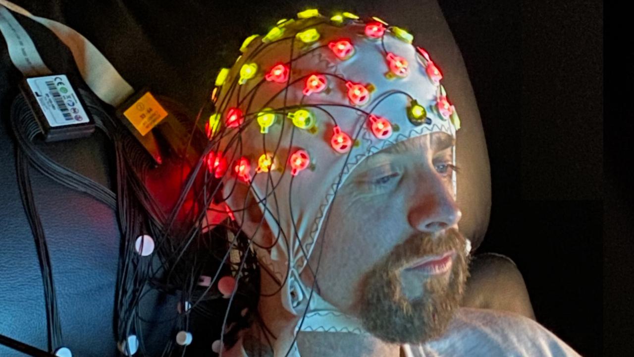 A man wears an EEG cap as he sits down