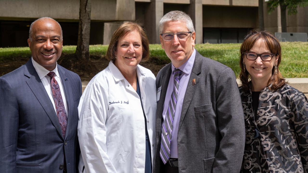 Deb Neff, in lab coat, flanked by Chancellor Gary S. May, left; and Dean Mark Winey and professor Kimberley McAllister. (Sasha Bakhter/UC Davis)