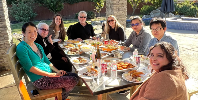 A group of eight people sitting on a patio outside eating a meal.
