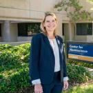 A woman in a navy suit smiles while standing outside near a UC Davis Center for Neuroscience sign.