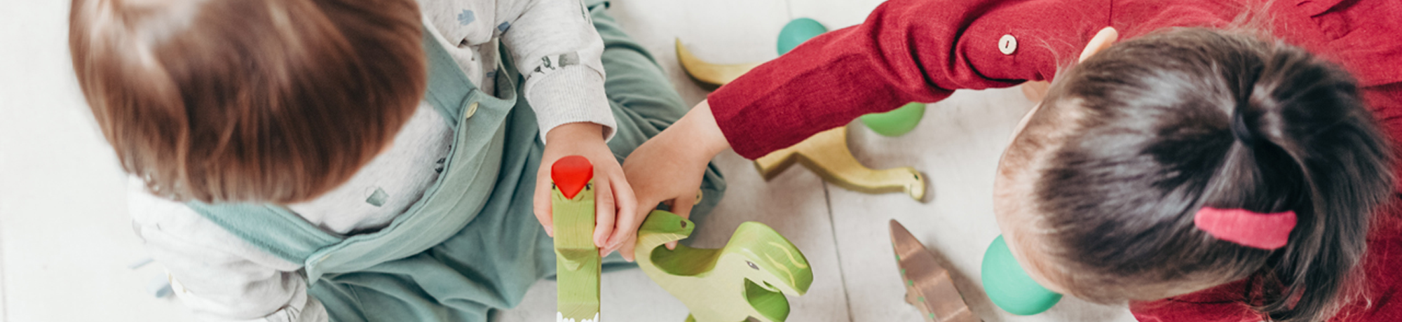 Two children playing with wooden dinosaurs